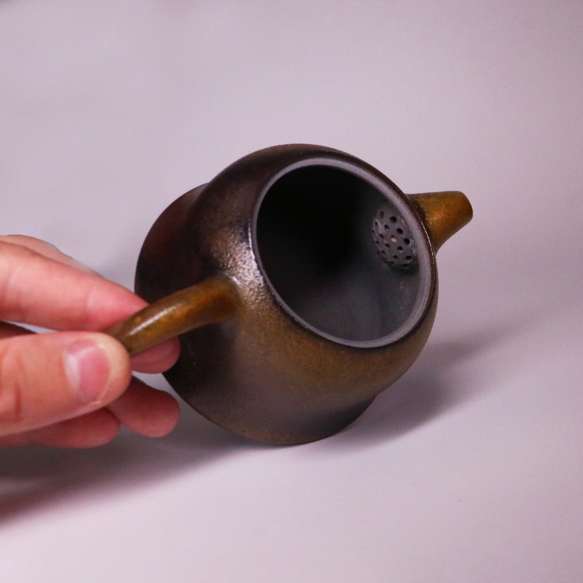 Hand holding artisan Rongchang Chinese pottery teapot made of pure handmade ceramics