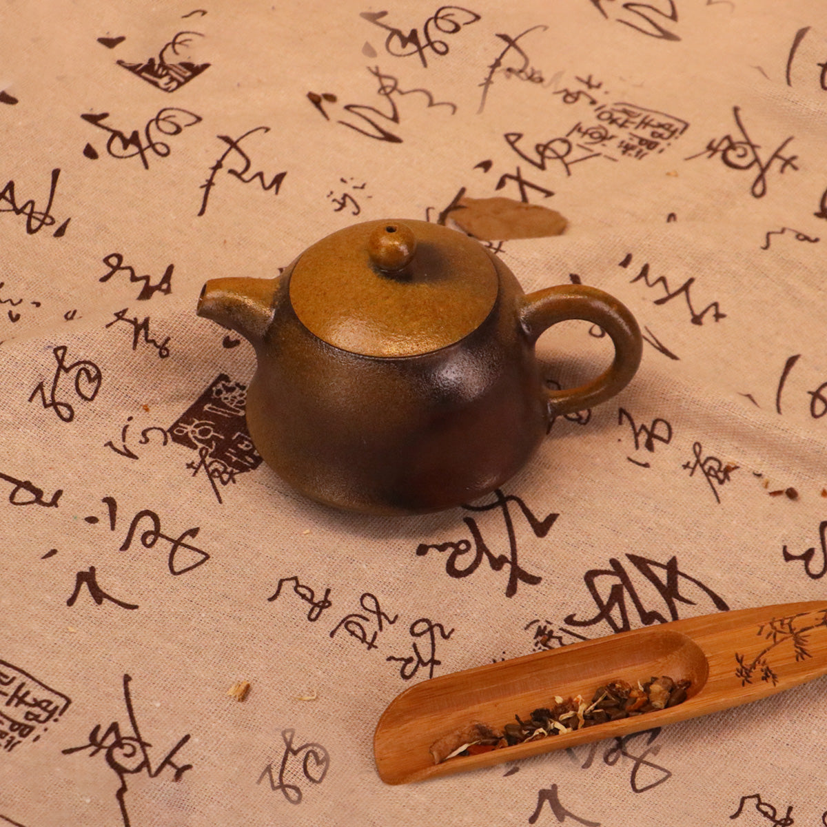 Artisan Rongchang Chinese pottery teapot in brown handmade ceramic on calligraphy fabric surface