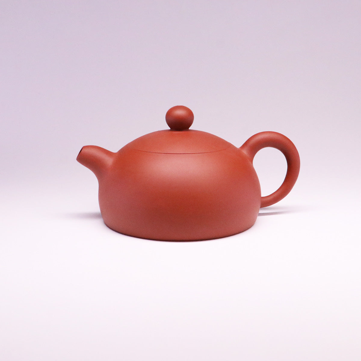 Handcrafted ceramic teapot in smooth reddish-brown finish with rounded body and handle