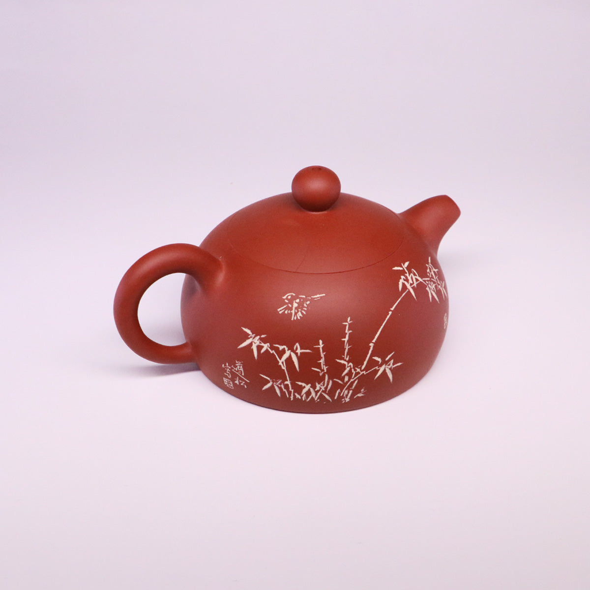 Handcrafted ceramic teapot in reddish-brown with bamboo design and round handle