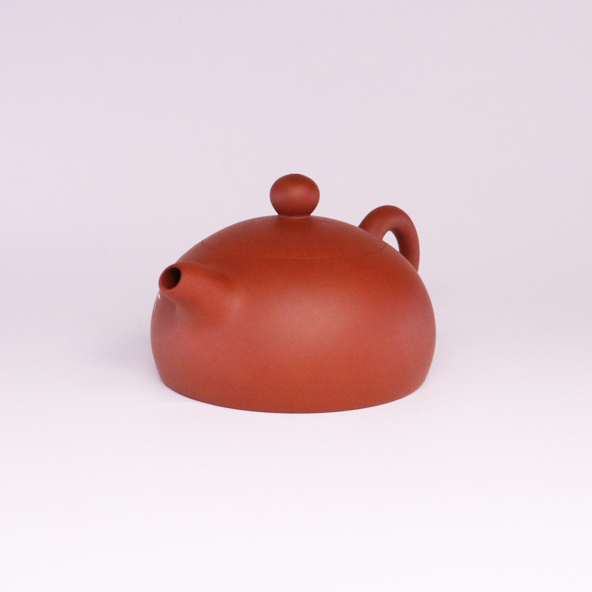 Handcrafted ceramic teapot in matte reddish-brown with rounded shape and smooth finish