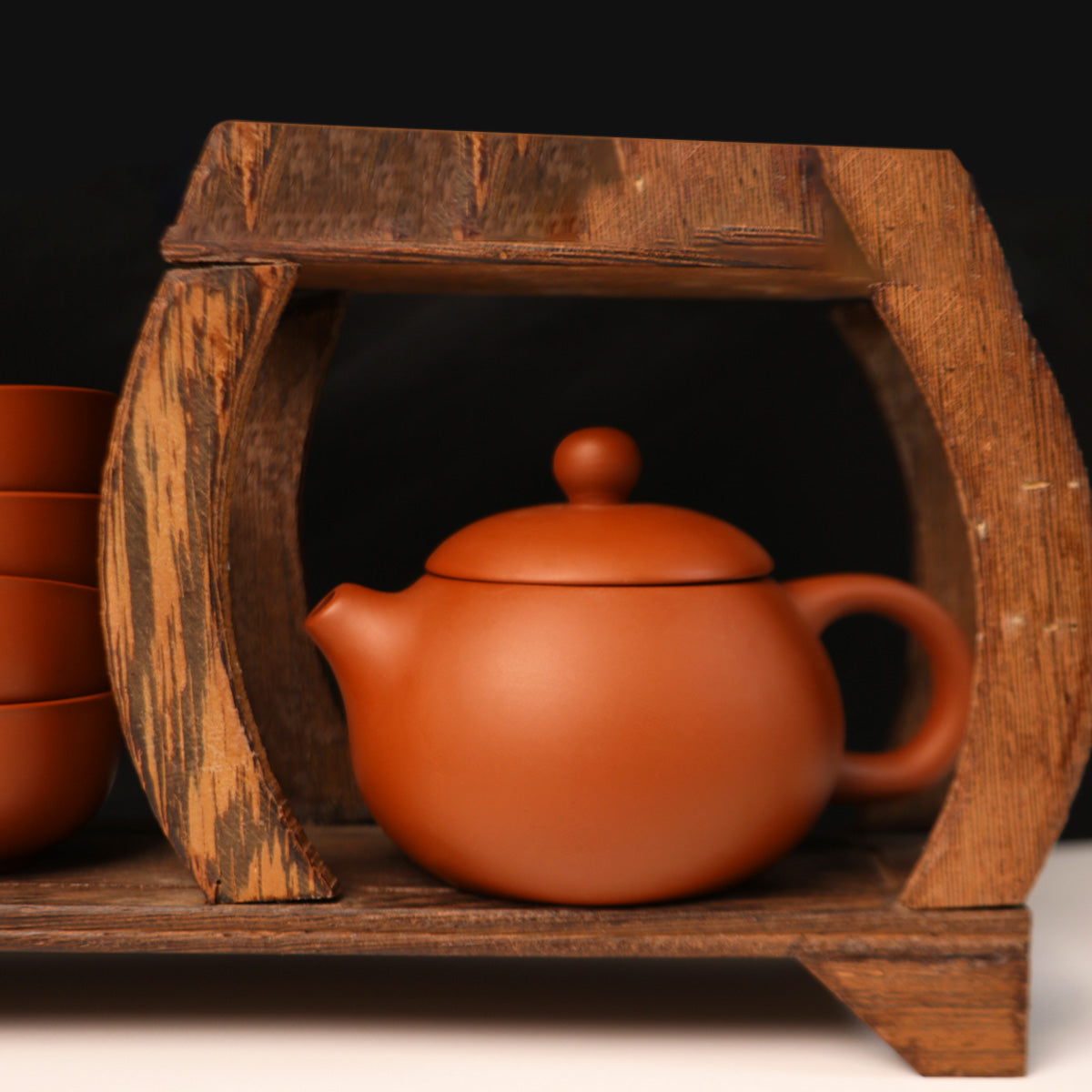 Handmade Rongchang ceramic teapot displayed on a wooden shelf with matching cups